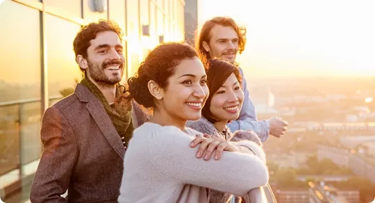 Four friends enjoying the sunset together on the balcony.