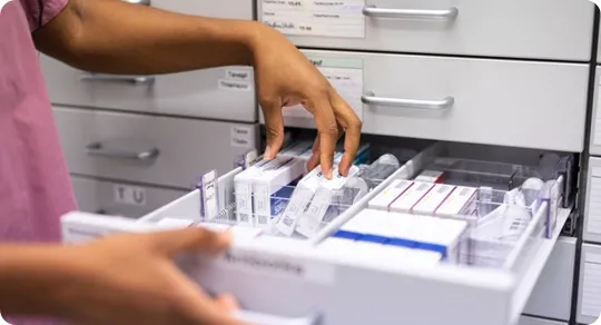 Pharmacist organizing drawer with medications.