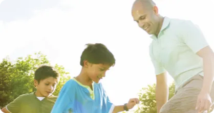 Father playing soccer with sons.