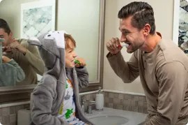 Father teaching his son how to brush teeth.