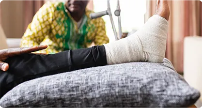 Man resting his leg on a pillow after bandaging it.